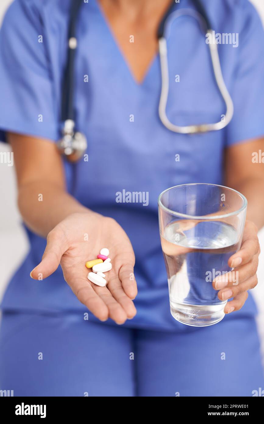Nehmen Sie zwei davon täglich mit Wasser. Zugeschnittenes Bild eines Arztes, der Pillen und ein Glas Wasser in der Hand hält. Stockfoto