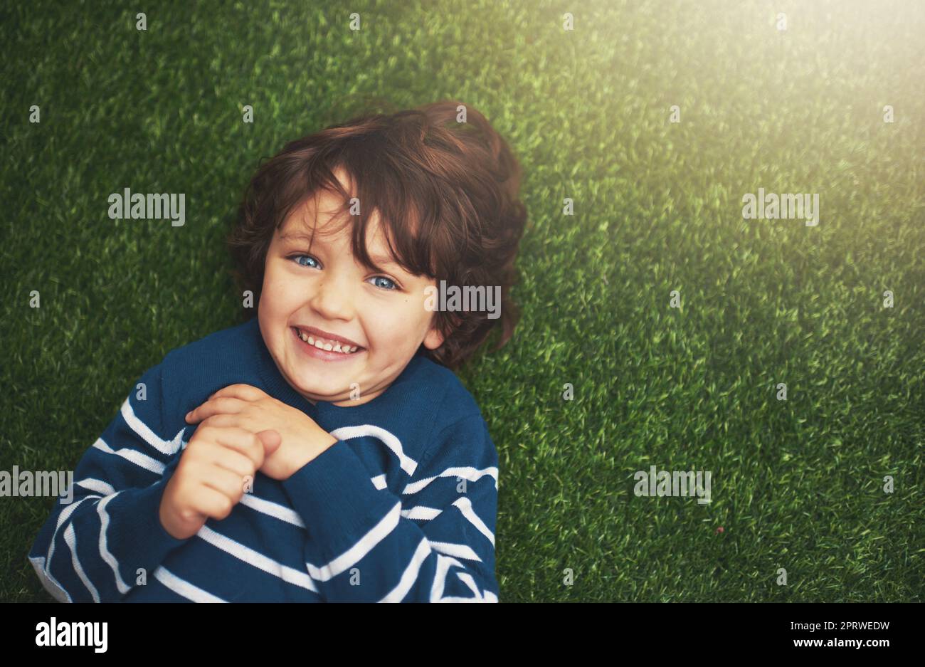 Ein kleiner Junge, der auf dem Gras liegt. Stockfoto