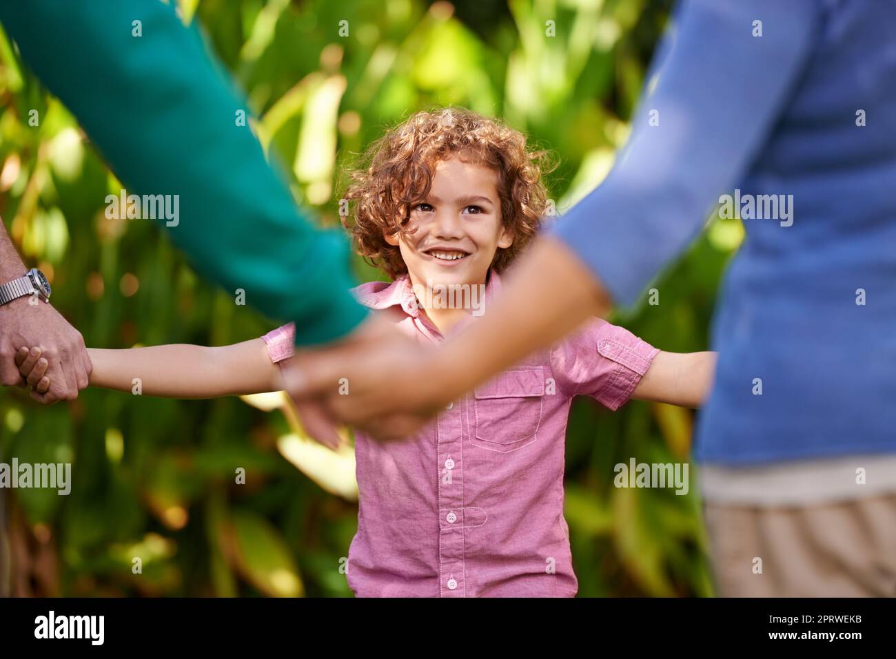 Ein kleiner Junge, der mit seiner Familie eine Partie Ring-a-Rosy genießt. Stockfoto