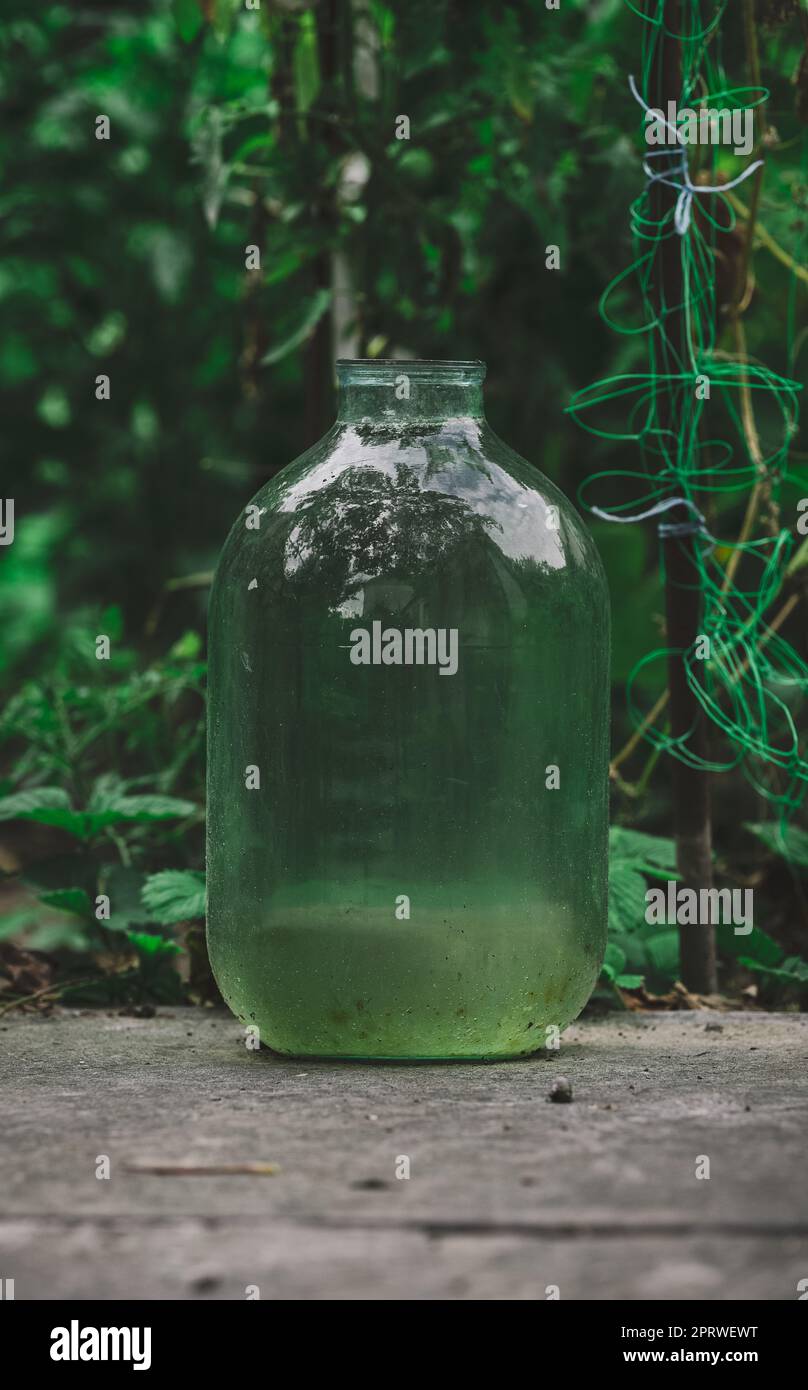 Im Garten steht eine glasklare zehn-Liter-Flasche Wasser Stockfoto