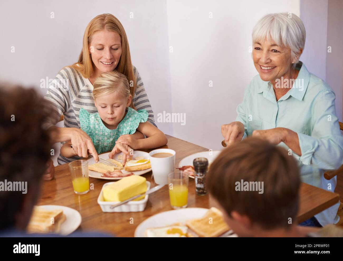Mütter sind ein Experte für Multitasking. Eine kurze Aufnahme einer glücklichen Familie aus mehreren Generationen, die zu Hause zusammen frühstücken kann. Stockfoto