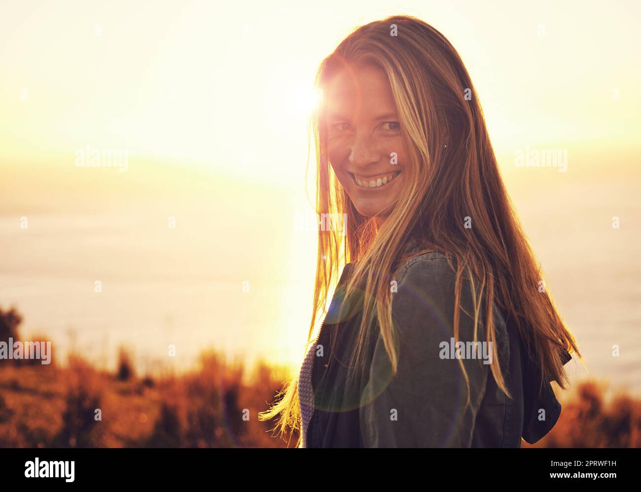 Abenteuer erwartet Sie. Porträt einer Frau, die bei Sonnenuntergang auf einem Hügel steht. Stockfoto