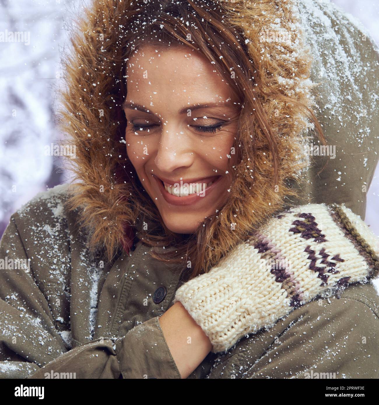 Liebe den ersten Schneefall. Eine attraktive Frau, die sich draußen im Schnee genießt. Stockfoto