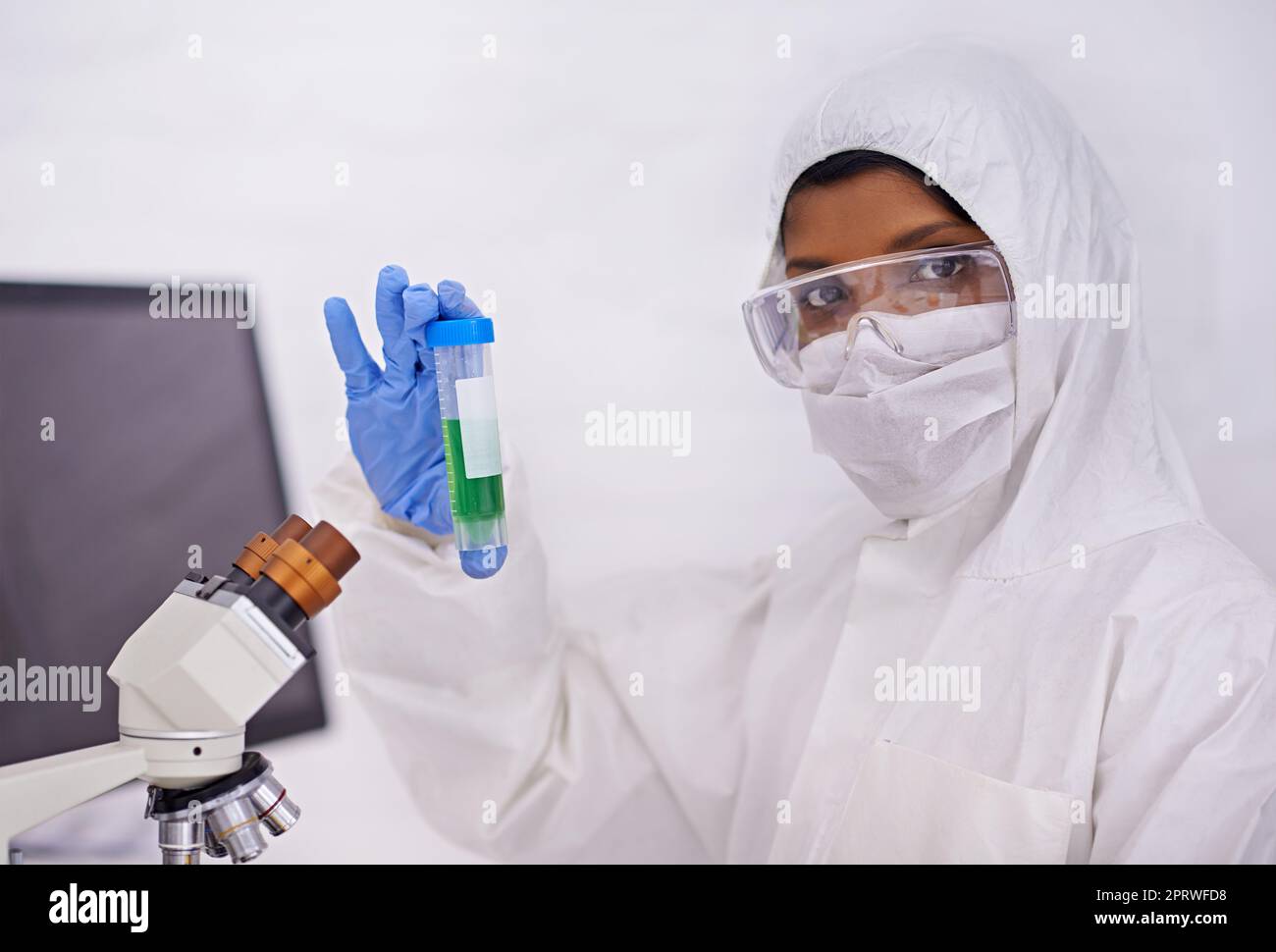 Raten Sie mal, was ich hier habe. Ein Porträt eines jungen Wissenschaftlers in Schutzkleidung, der ein Reagenzglas hochhält. Stockfoto