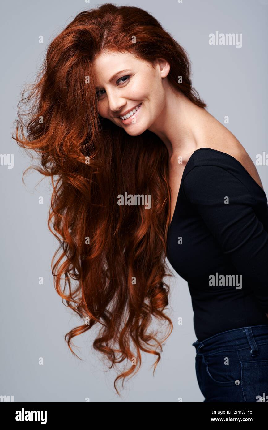 Das Leben ist nicht perfekt, aber zumindest meine Haare sind es. Studioaufnahme einer jungen Frau mit schönen roten Haaren, die vor einem grauen Hintergrund posiert. Stockfoto