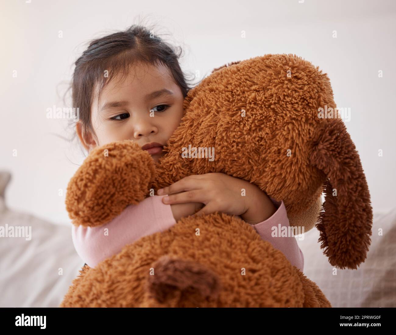 Kinder, Angst und Angst mit einem Mädchen, das ihren Teddybär hält, nach einem Albtraum in ihrem Schlafzimmer zu Hause. Kinder, Angst und Depression mit einem kleinen weiblichen Kind, das ein Stofftier in ihrem Haus umarmt Stockfoto
