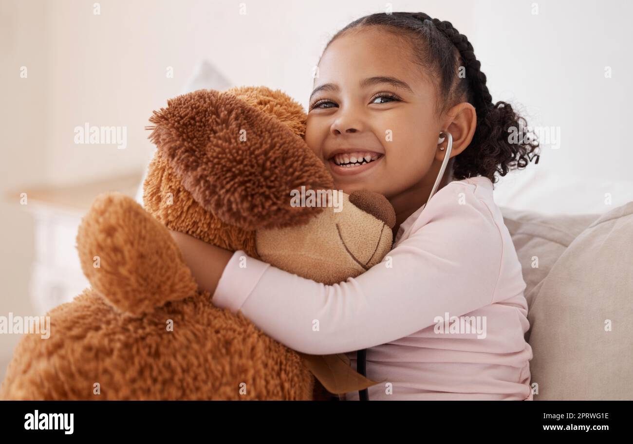 Kinder, Teddybär und Mädchen mit einem Kind, das ihr Stofftier mit einem Lächeln in ihrem Haus umarmt. Kinder, glücklich und sicher mit einer niedlichen oder niedlichen Frau, die ein flauschiges Spielzeug hält, während sie auf einem Bett sitzen Stockfoto