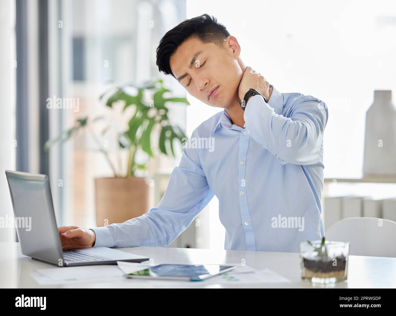 Stress, Burn-out und Nackenschmerzen asiatischer Mann mit Kopfschmerzen, Angst und Depressionen, der mit einem Laptop in einem Bericht, einer Steuer oder einem Audit im Büro arbeitet. Frustrierter und müder Geschäftsmann mit psychischer Gesundheit überarbeitet Stockfoto