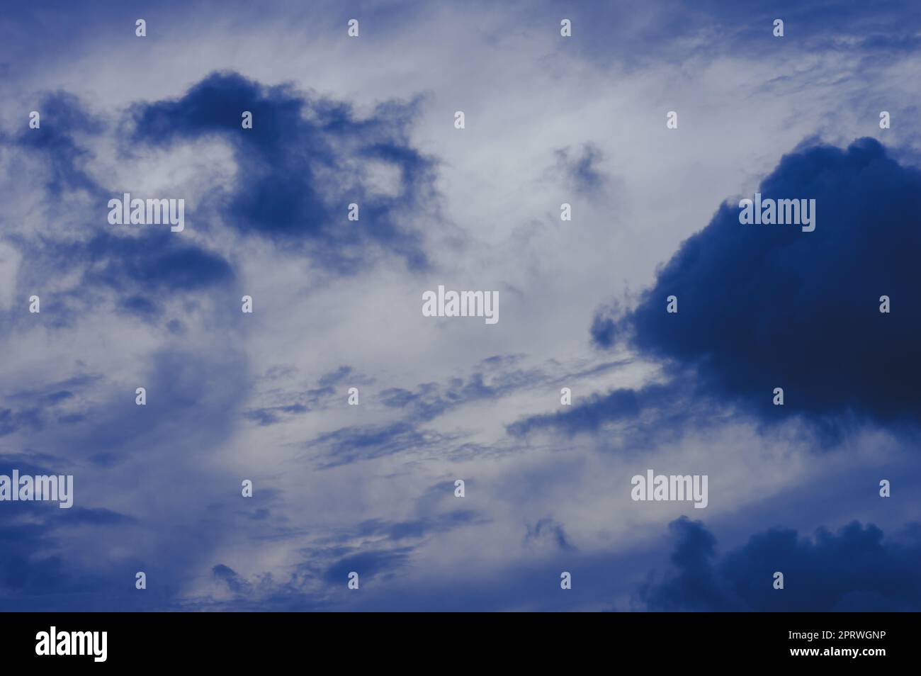 Dunkle Wolken im Hintergrund des blauen Himmels. Dunkle Regenwolken, die am Himmel bei Sonnenuntergang schwimmen. Natur Hintergrund. Stockfoto