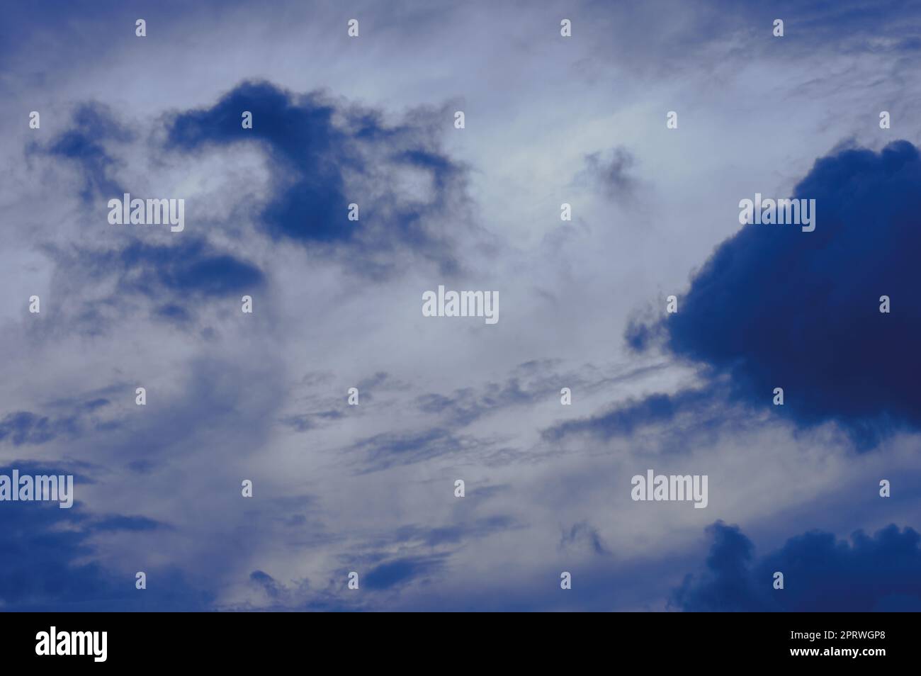 Dunkle Wolken im Hintergrund des blauen Himmels. Dunkle Regenwolken, die am Himmel bei Sonnenuntergang schwimmen. Natur Hintergrund. Stockfoto