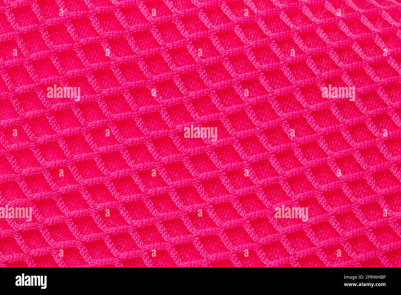 Rote Stoffstruktur. Nahaufnahme eines elastischen, scharlachroten Nylongewebes mit nahtlosem Muster für Sportgeräte, Rucksäcke, Taschen oder andere Kleidungsstücke. Makro. Stockfoto