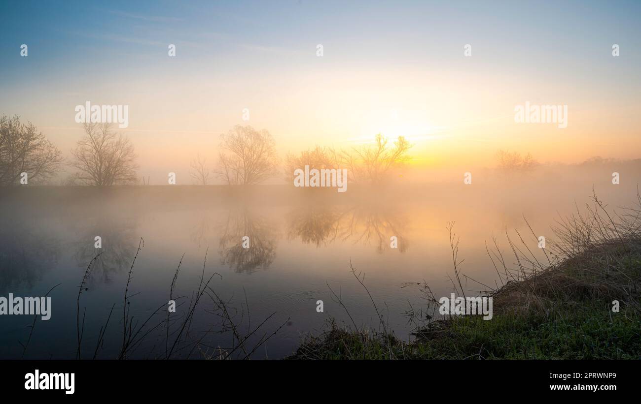 Goldener Sonnenaufgang mit Nebel am Fluss im März Stockfoto