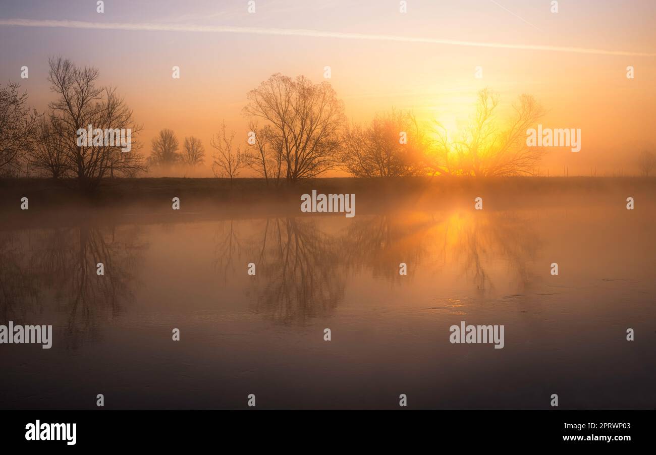 Goldener Sonnenaufgang mit Nebel am Fluss im März Stockfoto