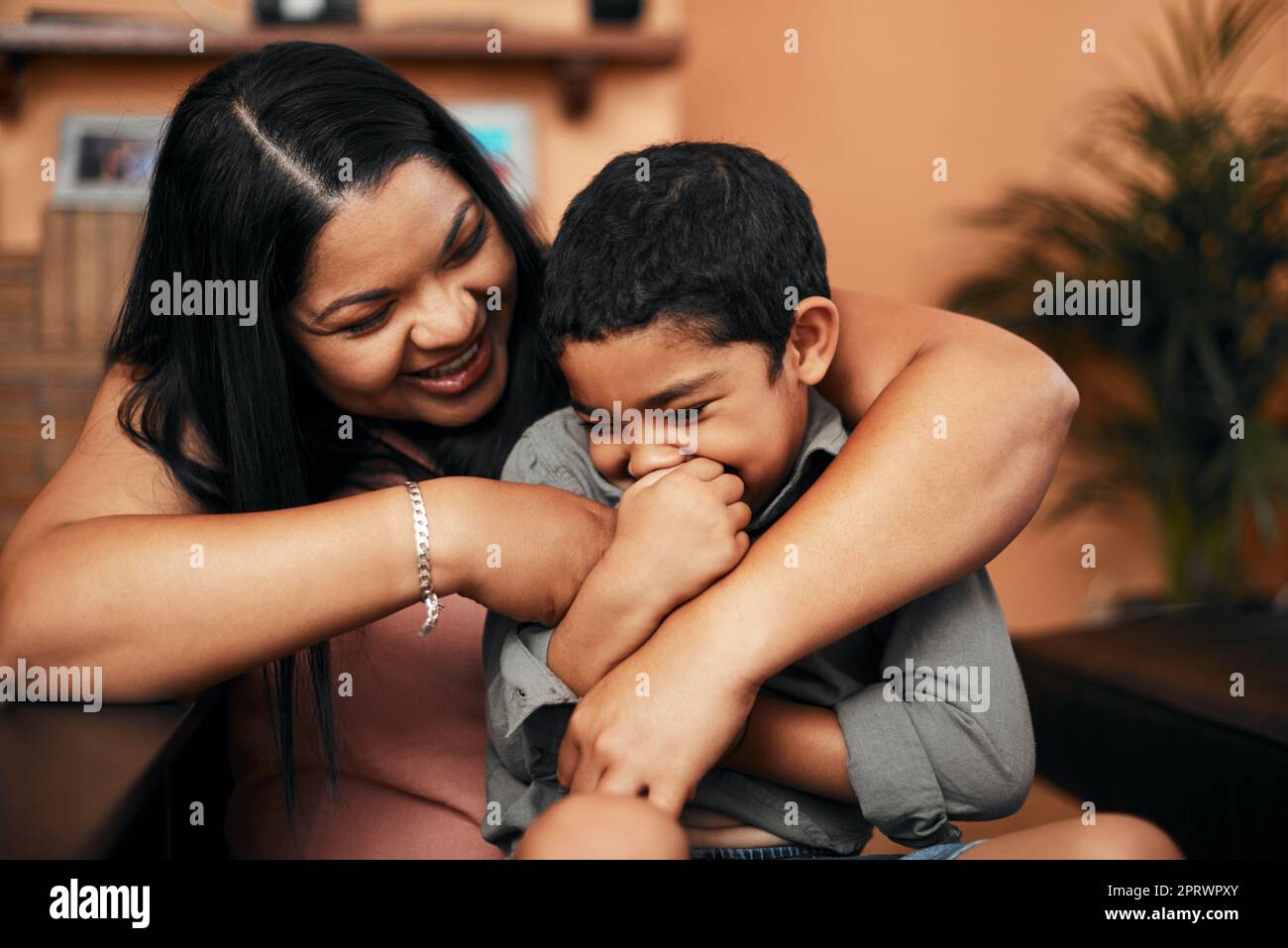 Mama lässt ihn kichern mit ihrem Kitzeln. Eine Mutter kitzelt ihren kleinen Sohn zu Hause. Stockfoto