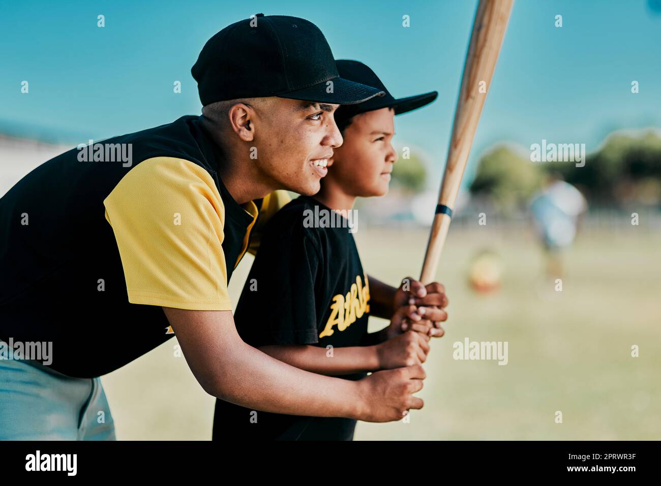 Ein junger Baseballspieler zeigt einem kleinen Jungen, wie man spielt. Stockfoto