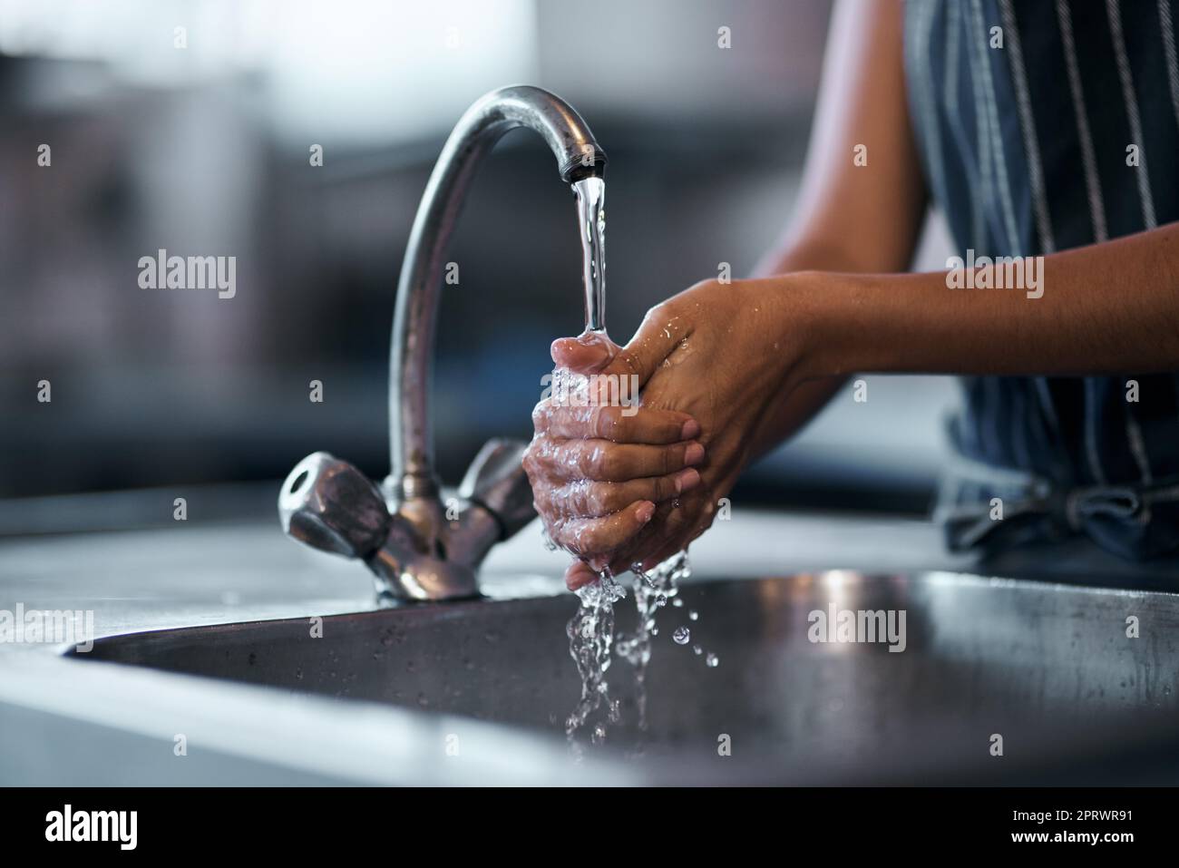 Der Gesundheitsinspektor wäre sehr stolz: Eine Frau, die sich im Waschbecken einer kommerziellen Küche die Hände wusch. Stockfoto