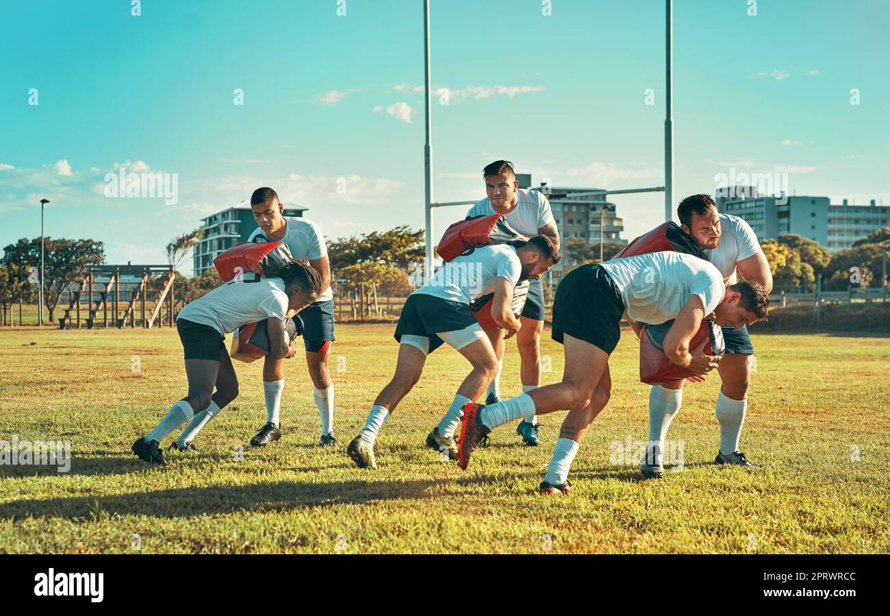 Arbeiten an der Verbesserung ihrer Tackling-Fähigkeiten. Eine Gruppe von Rugby-Spielern, die mit Tackle Bags auf dem Feld trainieren. Stockfoto
