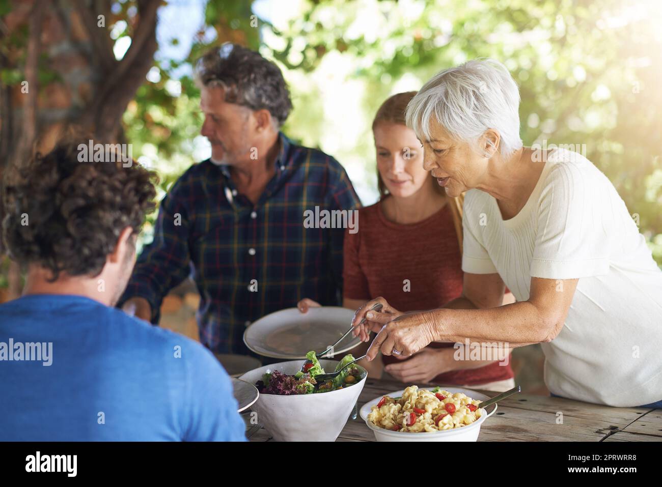 Lassen Sie mich für Sie aufbereiten ... eine Familie, die sich darauf vorbereitet, gemeinsam im Freien zu essen. Stockfoto
