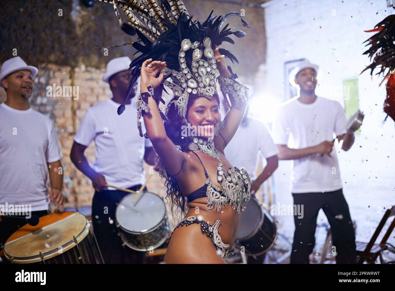 Federvögel. Eine attraktive ethnische Frau in einem Perlenkostüm und einem riesigen Federkopfschmuck, der tanzt. Stockfoto