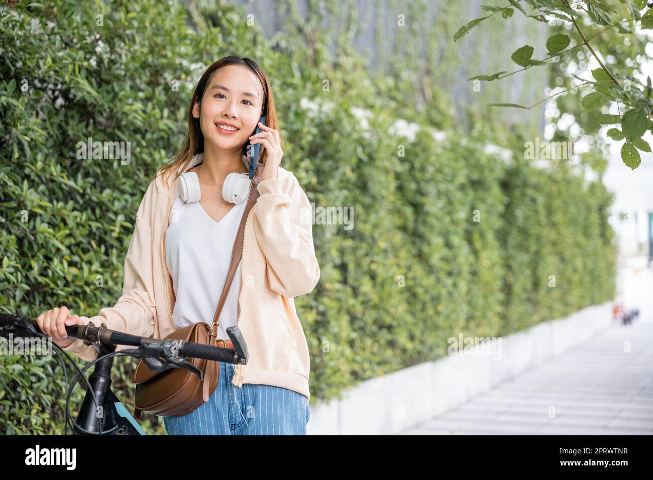 Eine Frau, die mit ihrem Fahrrad auf dem Land unterwegs ist und mit einem Freund telefoniert Stockfoto