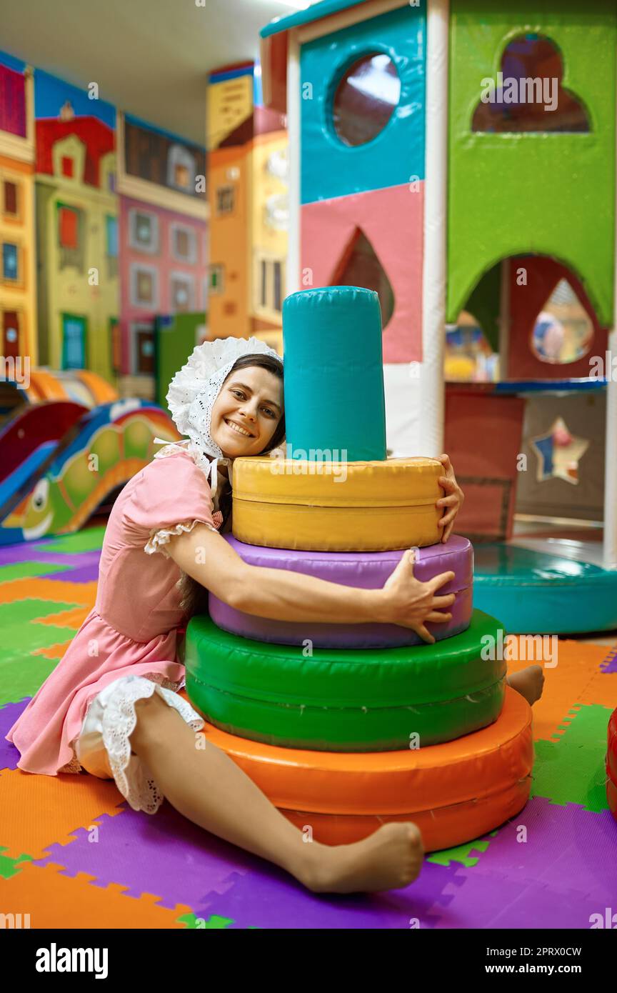 Nette Frau wie kleines Baby umarmt mit weichen Spielzeug Pyramide Stockfoto