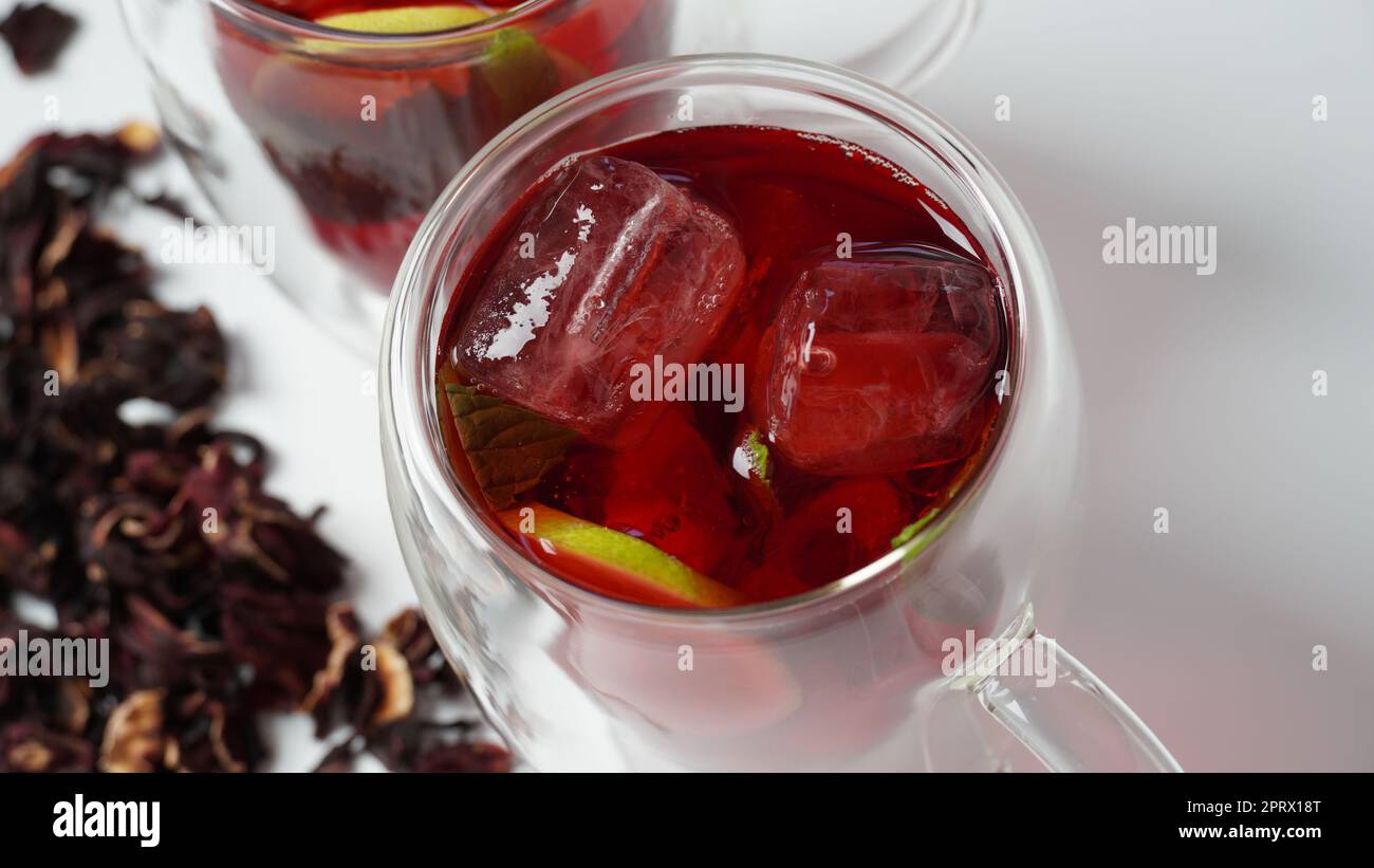 Hibiscus kaltes Teetrink mit Eiswürfeln und Zitrone im Glas Stockfoto