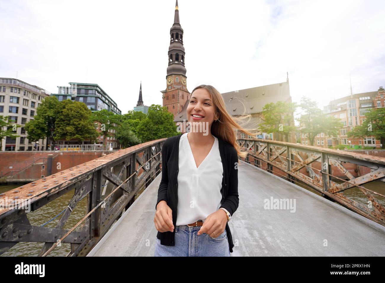 Porträt einer lächelnden jungen Frau, die auf einer Brücke in Hamburg läuft Stockfoto