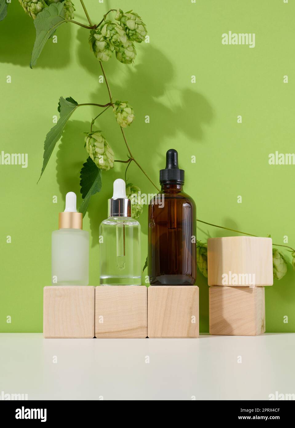 Drei Glasflaschen mit Pipetten für Kosmetika, Säuren, Öle auf grünem Hintergrund. Leere Container Stockfoto