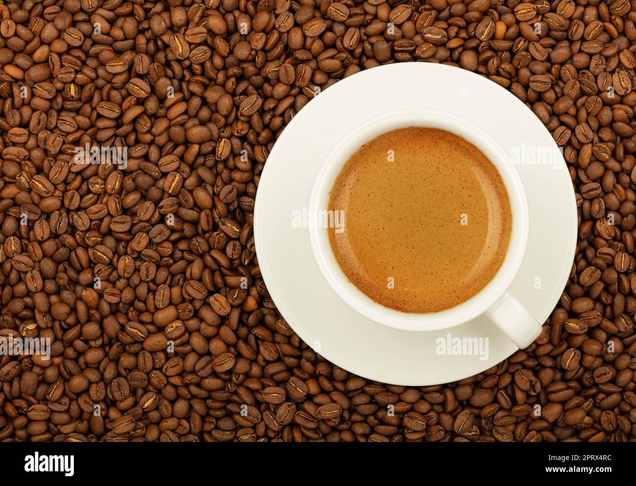 Weißer Espresso über gerösteten Kaffeebohnen Stockfoto