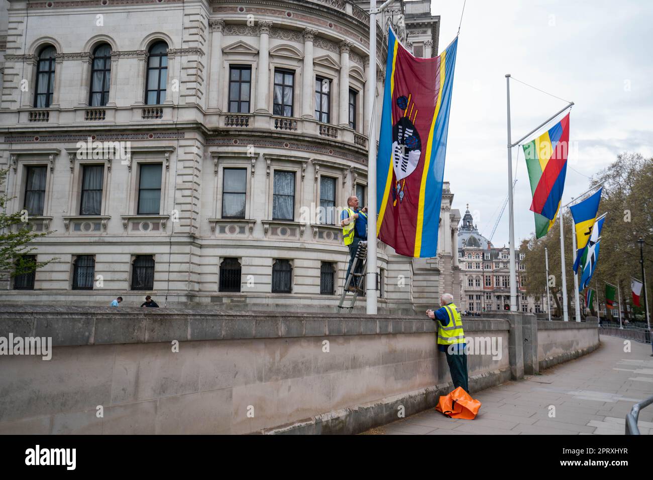 London Großbritannien. 27. April 2023. Ein Fahnenmast-Ingenieur befestigt die Flagge Swasilands und Flaggen anderer Commonwealth-Nationen an Pferdewachen, um die Krönung von König Karl III. In der Westminster Abbey am 6. Mai vorzubereiten Stockfoto