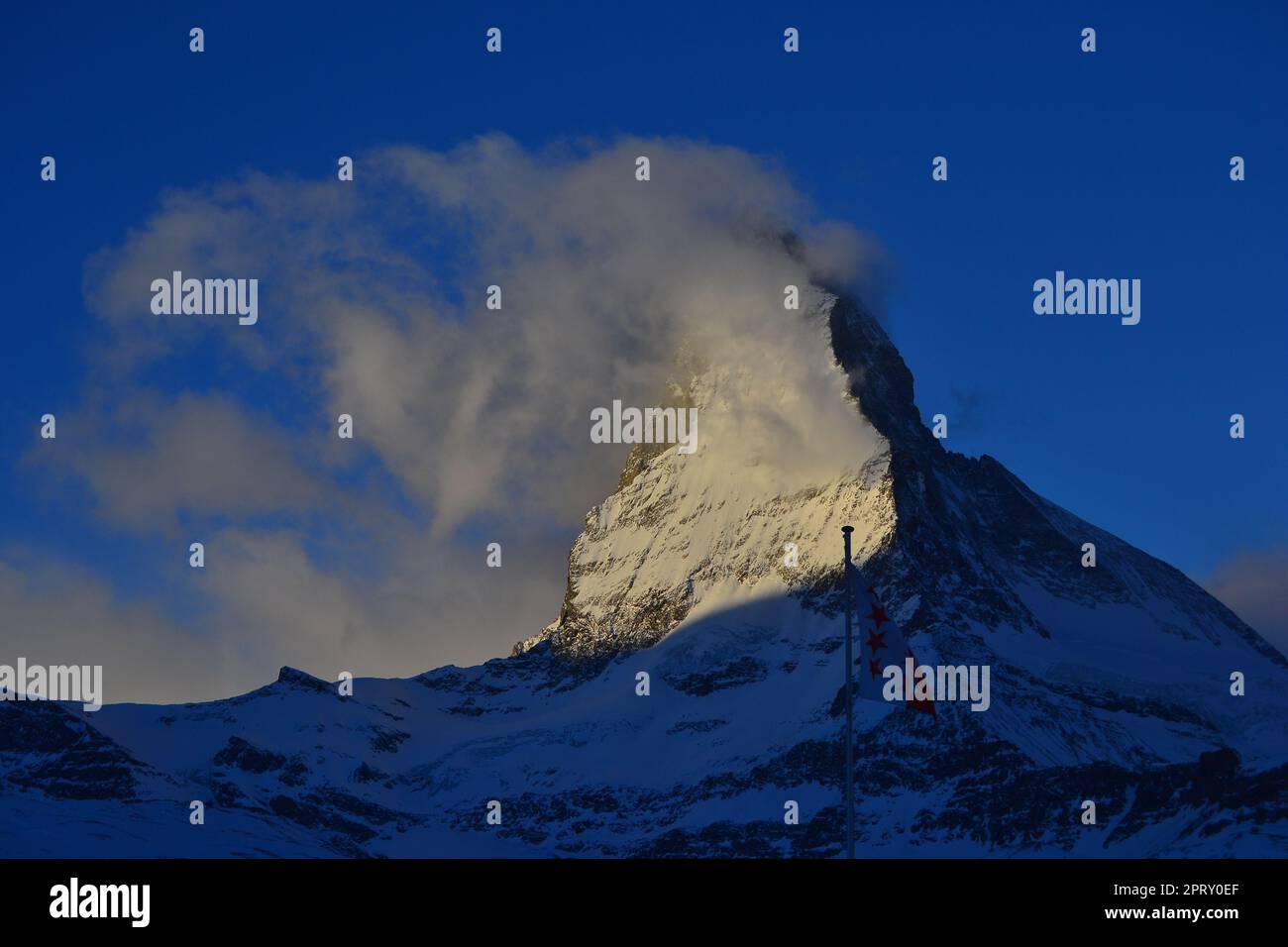 Das Matterhorn mit mystischen Wolken und blauem Himmel mit einer Flagge von wallis davor Stockfoto