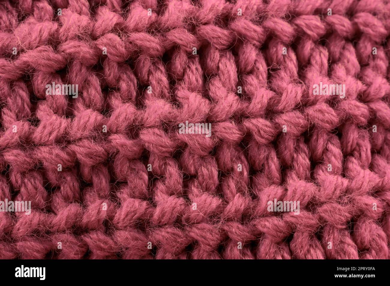 Rosafarbenes, handgefertigtes Strickmaterial mit Textilhintergrund. Stockfoto