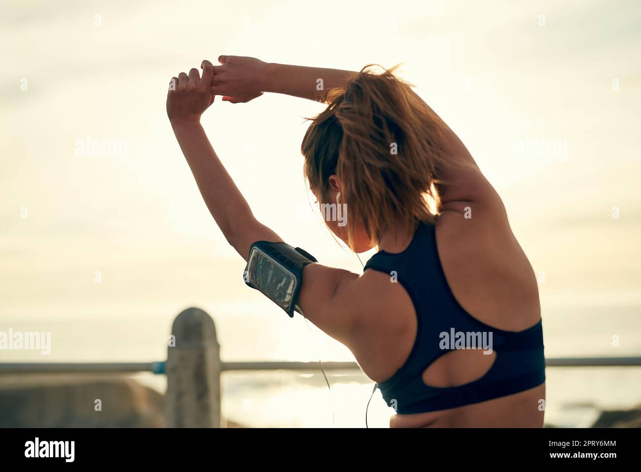 Dehnen Sie sich. Eine junge sportliche Frau, die draußen rennt Stockfoto