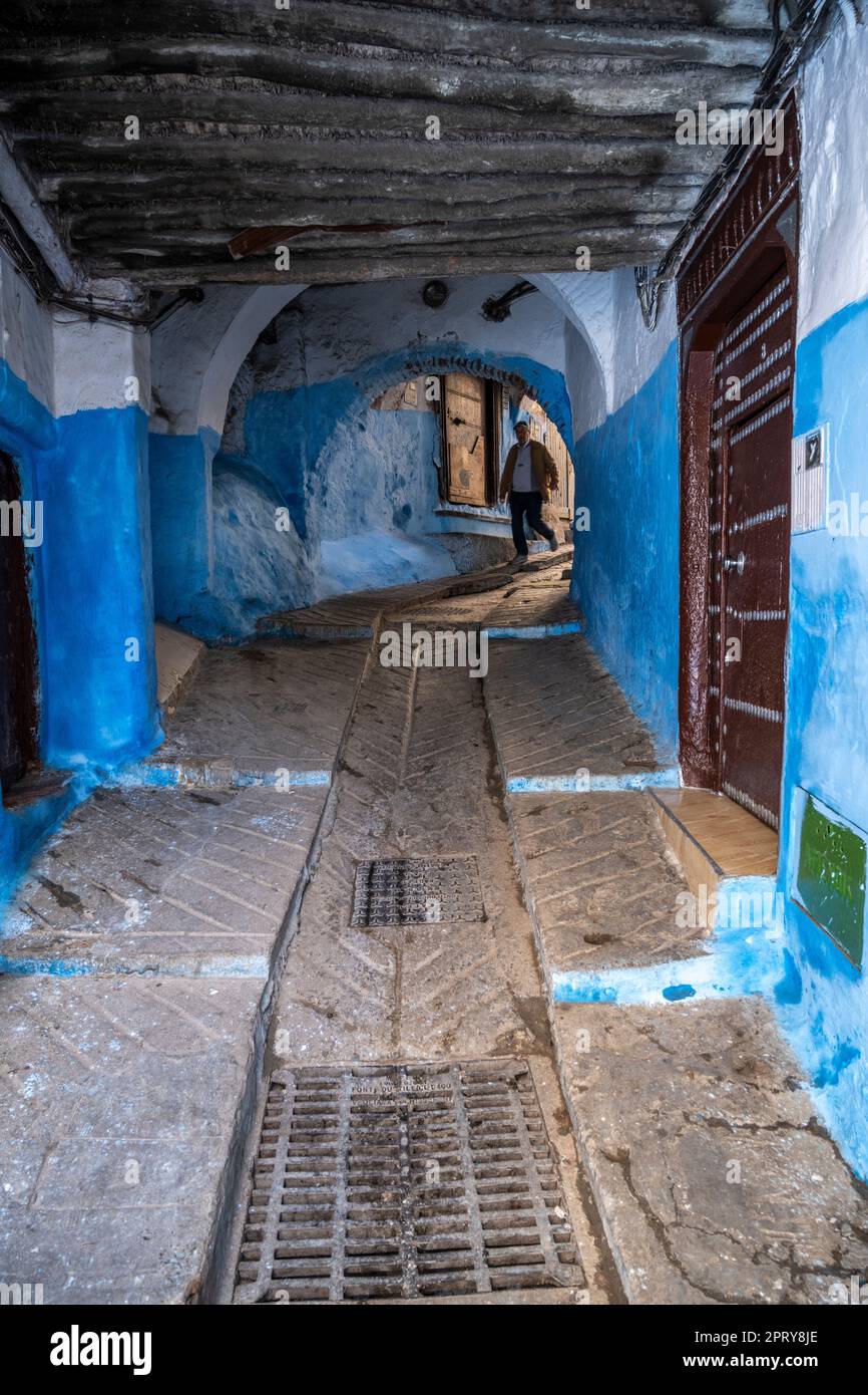 Ein Mann, der die Treppe einer steilen Gasse in der Medina von Tetouan hinuntergeht. Stockfoto