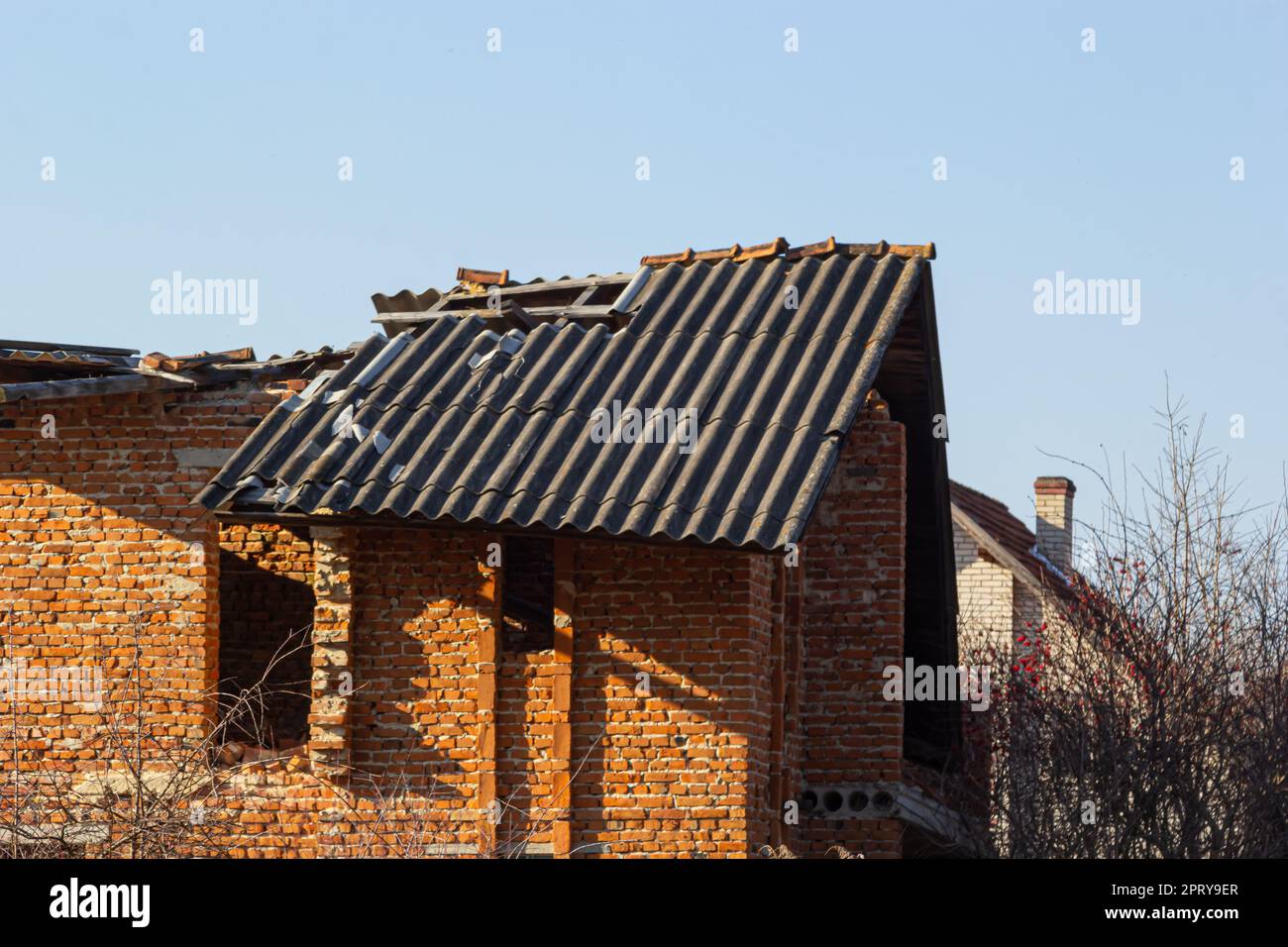 Das Dach des Ziegelhauses wurde zerstört. Das Haus wurde nach einem Sturm oder infolge von Granaten zerstört. Stockfoto