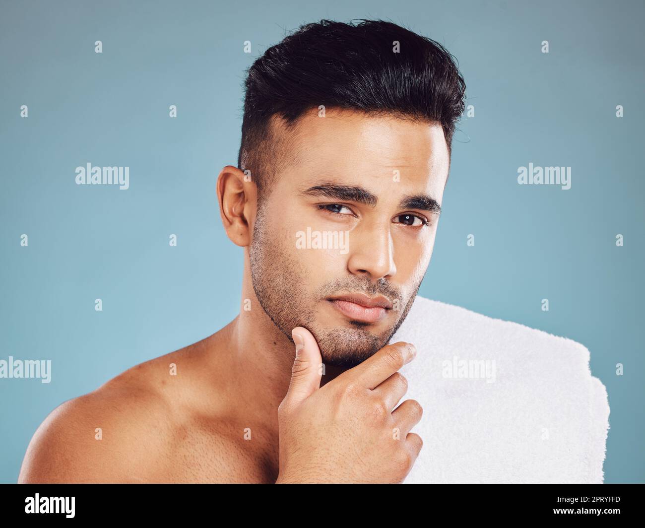 Mann, Hand-an-Gesicht und Hautpflegemittel-Putze oder Kosmetikporträt im Studio. Junges indisches Modell, gesunde Gesichtspflege und Körper Haut Entgiftung oder Wellness Stockfoto