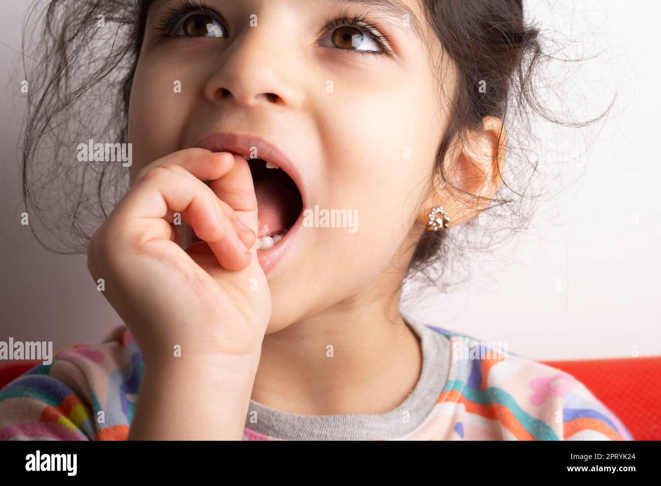 Kleines Mädchen Porträt versucht, lose Milchzahn, Nahaufnahme zu entfernen. Stockfoto