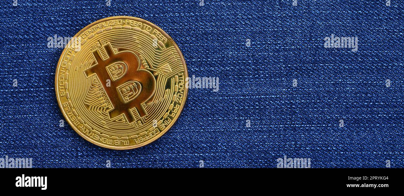 Goldene Bitcoin liegt auf blauem Jeans-Stoff. Neues virtuelles Geld. Neue Kryptowährung in Form der Münzen Stockfoto