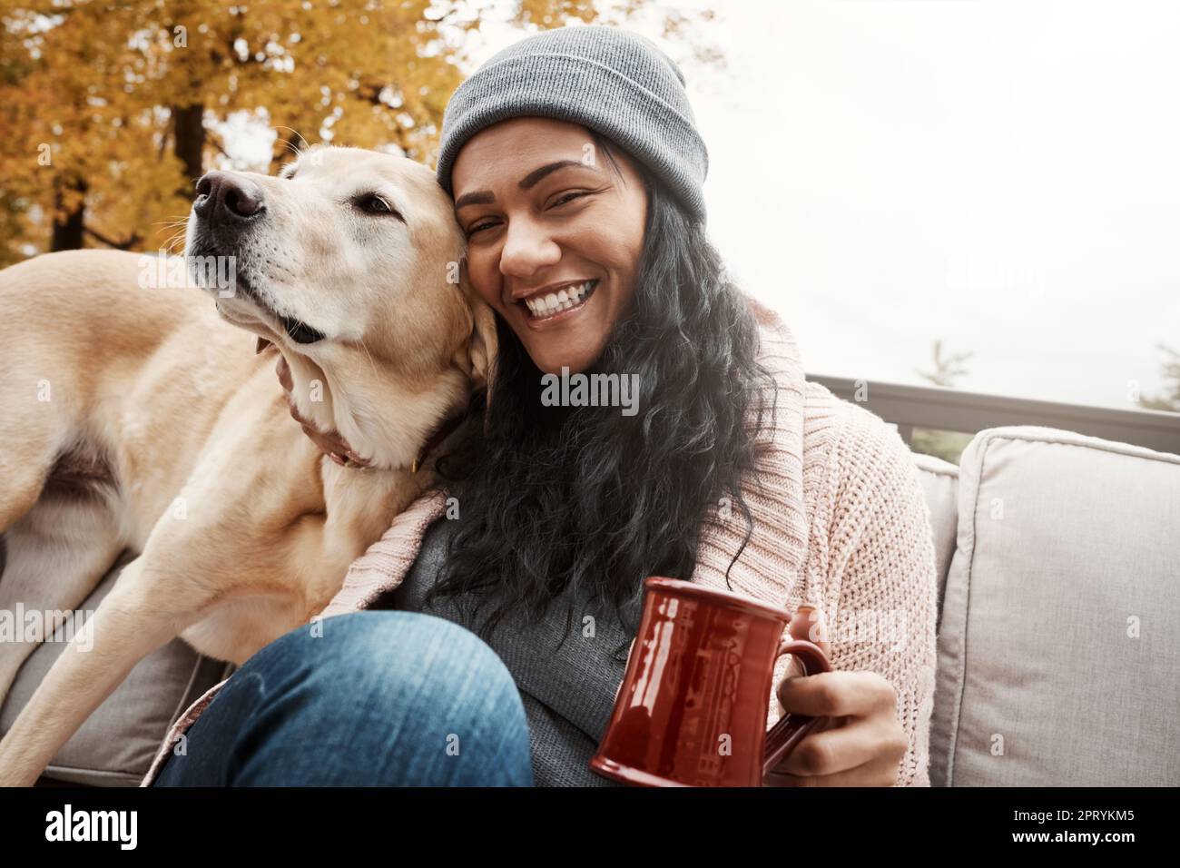 Hunde füllen nicht nur das Herz - sie machen es auch stärker. Eine junge Frau, die sich mit ihrem Hund draußen entspannt. Stockfoto