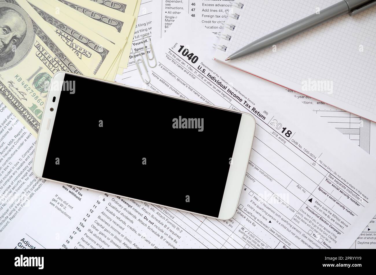 Zusammensetzung der Elemente liegen auf dem 1040 Steuerformular. Dollarscheine, pen, Smartphone, Büroklammer und Notepad. Reinigen Bildschirm schwarz Smartphone für Text placeme Stockfoto