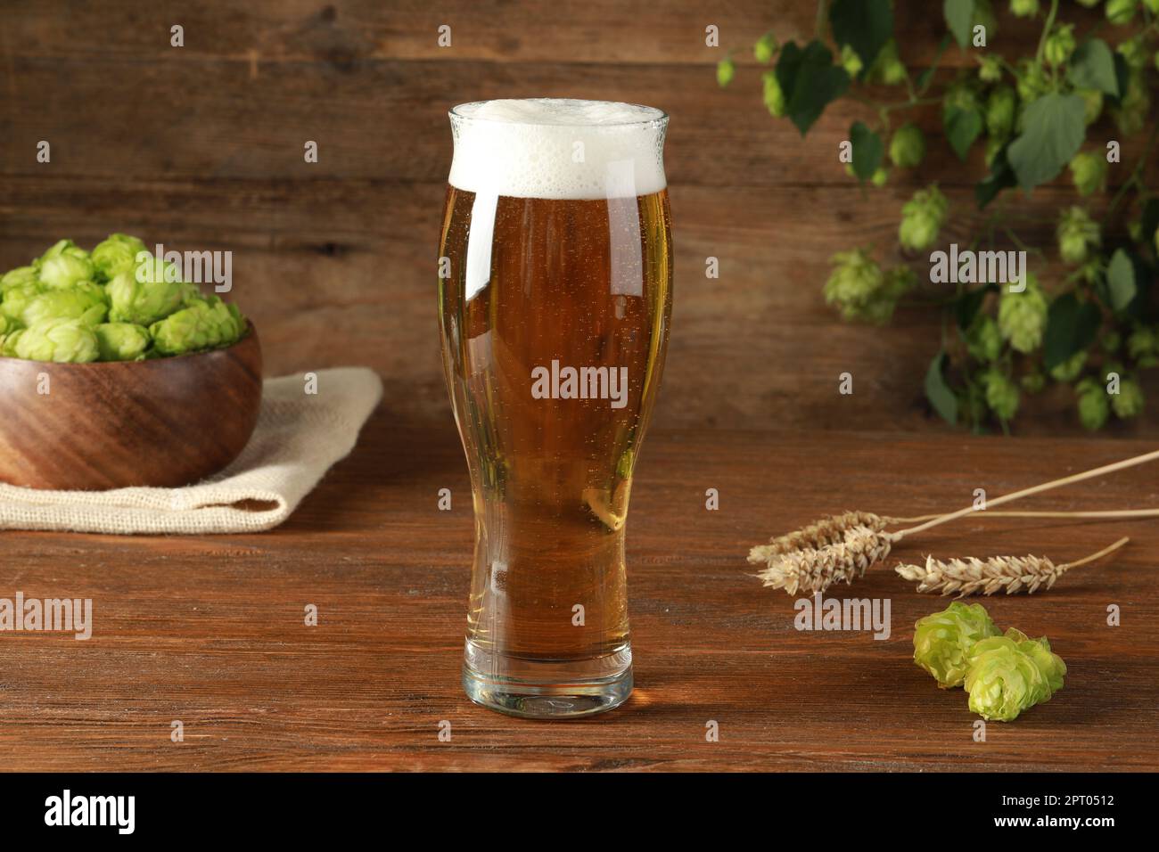 Ein Glas Bier, frischer grüner Hopfen und Stacheln auf einem Holztisch Stockfoto