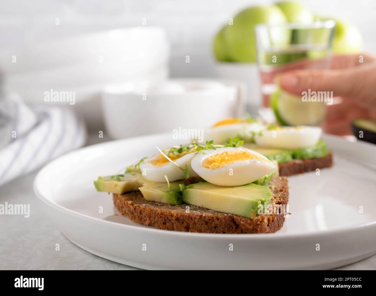 Avocado-Ei-Sandwich auf Roggenbrot auf hellem Tischhintergrund Stockfoto