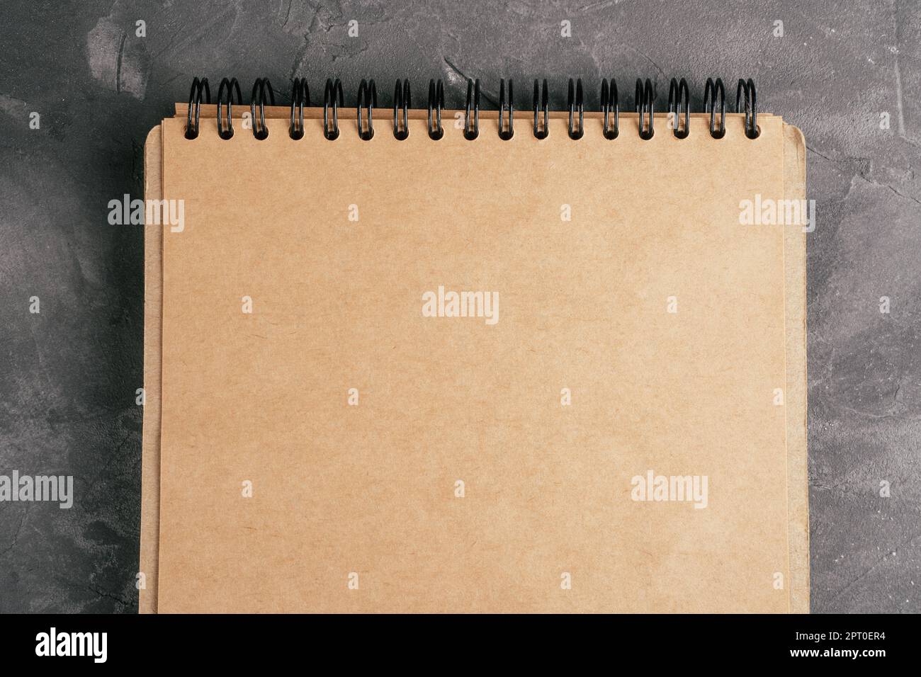 Geöffnetes braunes Kraftpapier-Notizbuch auf Feder auf grauer Betonoberfläche. Draufsicht. Speicherplatz kopieren Stockfoto
