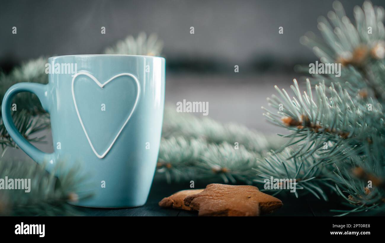 Teilweise verschwommener blauer Becher mit Herz mit Christbaumzweigen und Lebkuchen. Speicherplatz kopieren. Stockfoto