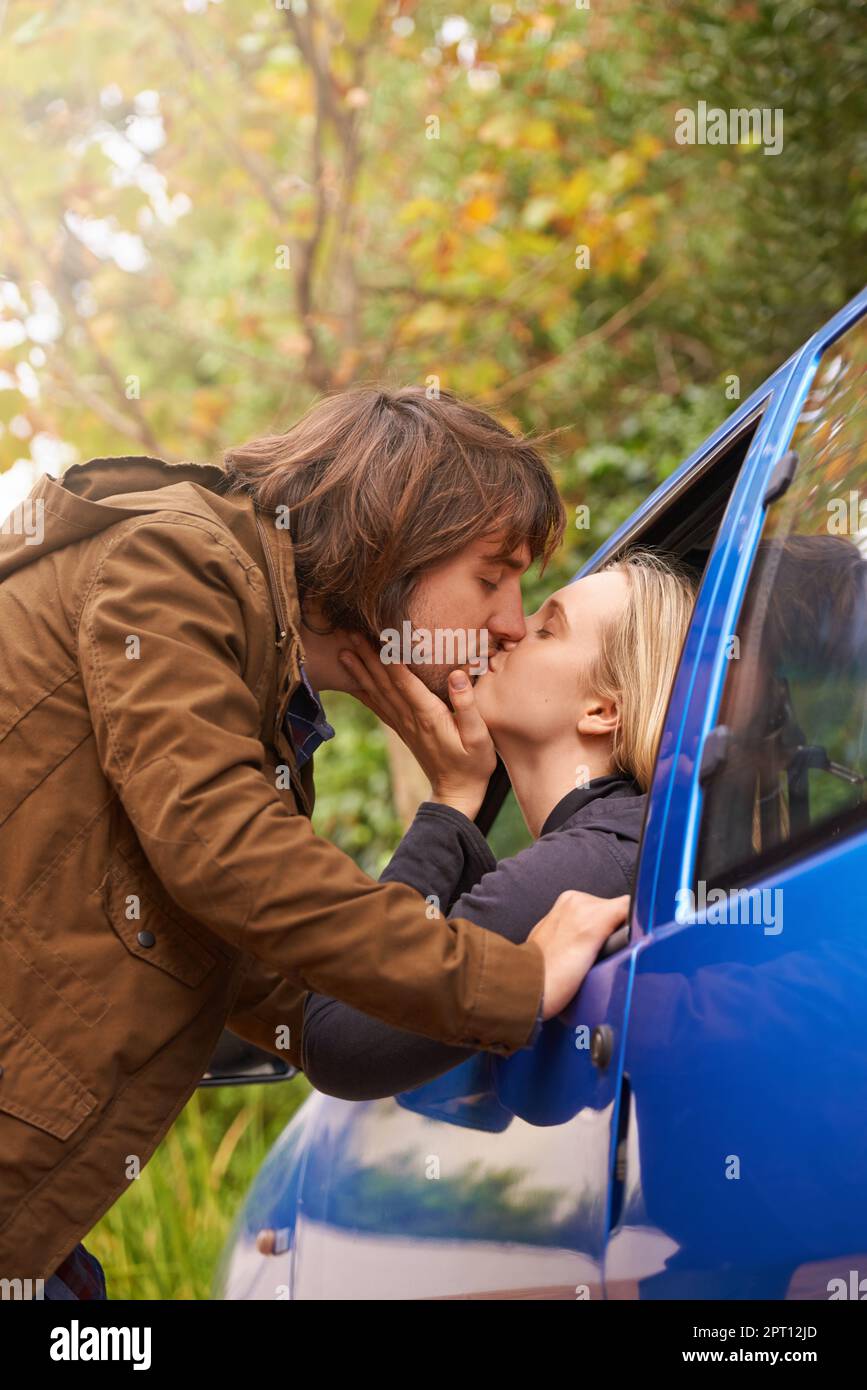 Liebe ist nur ein Wort, bis jemand Besonderes ihm Bedeutung gibt. Ein junger Mann, der sich zum Autofenster seiner Freundinnen beugte, um sich zu küssen Stockfoto