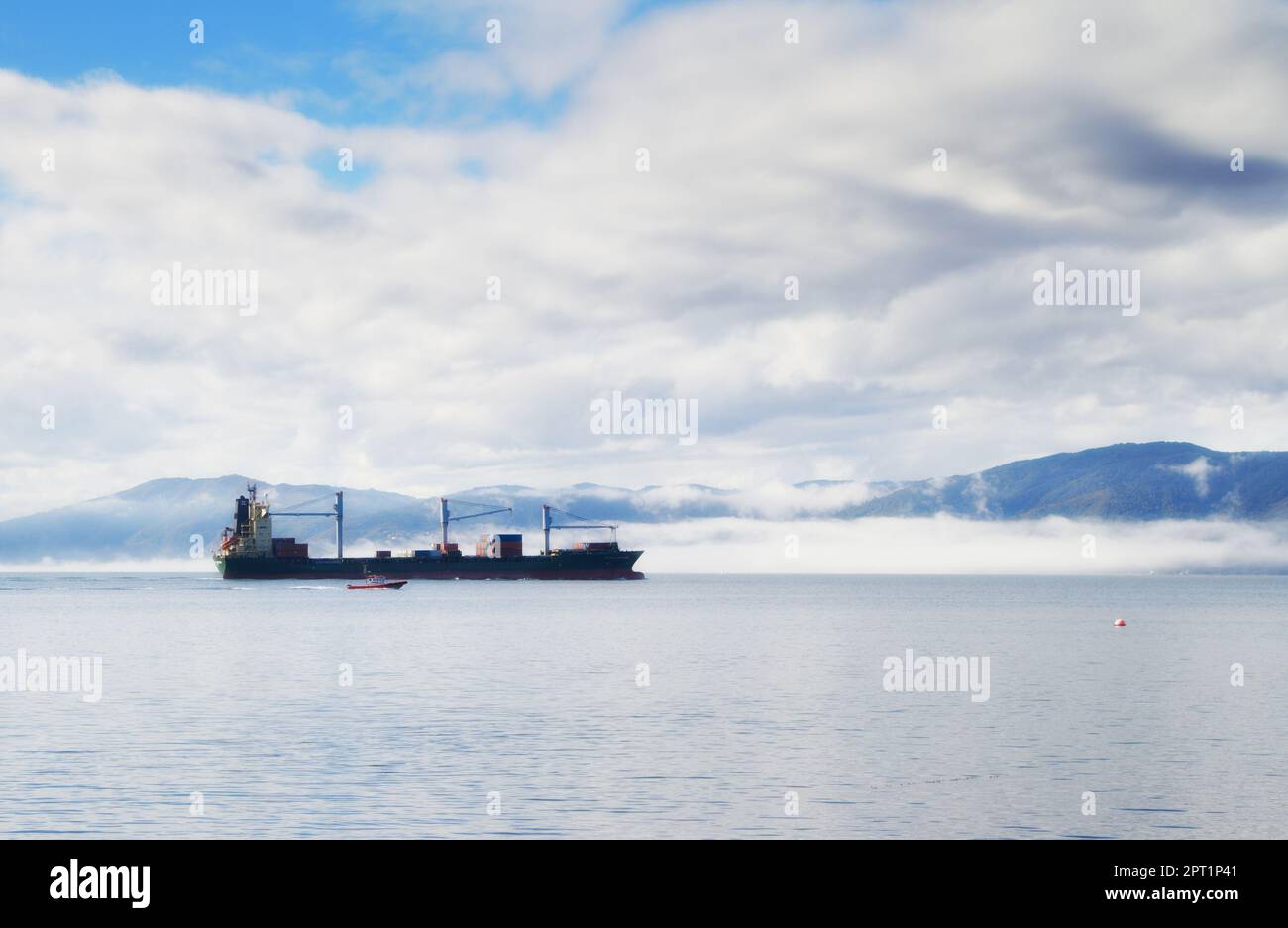 Sie transportieren wertvolle Fracht. Ein Frachtschiff, das entlang der Küstenlinie fährt Stockfoto