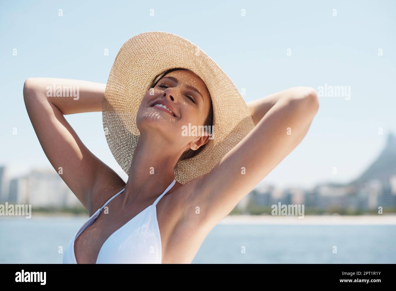 Ich fühle die Wärme und liebe sie. Eine attraktive junge Frau, die im Bikini draußen steht Stockfoto