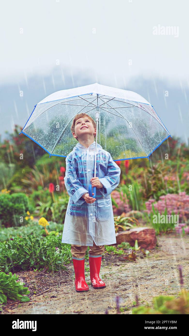 Mein Garten liebt den Regen. Die volle Länge eines jungen Mannes, der draußen im Regen steht Stockfoto