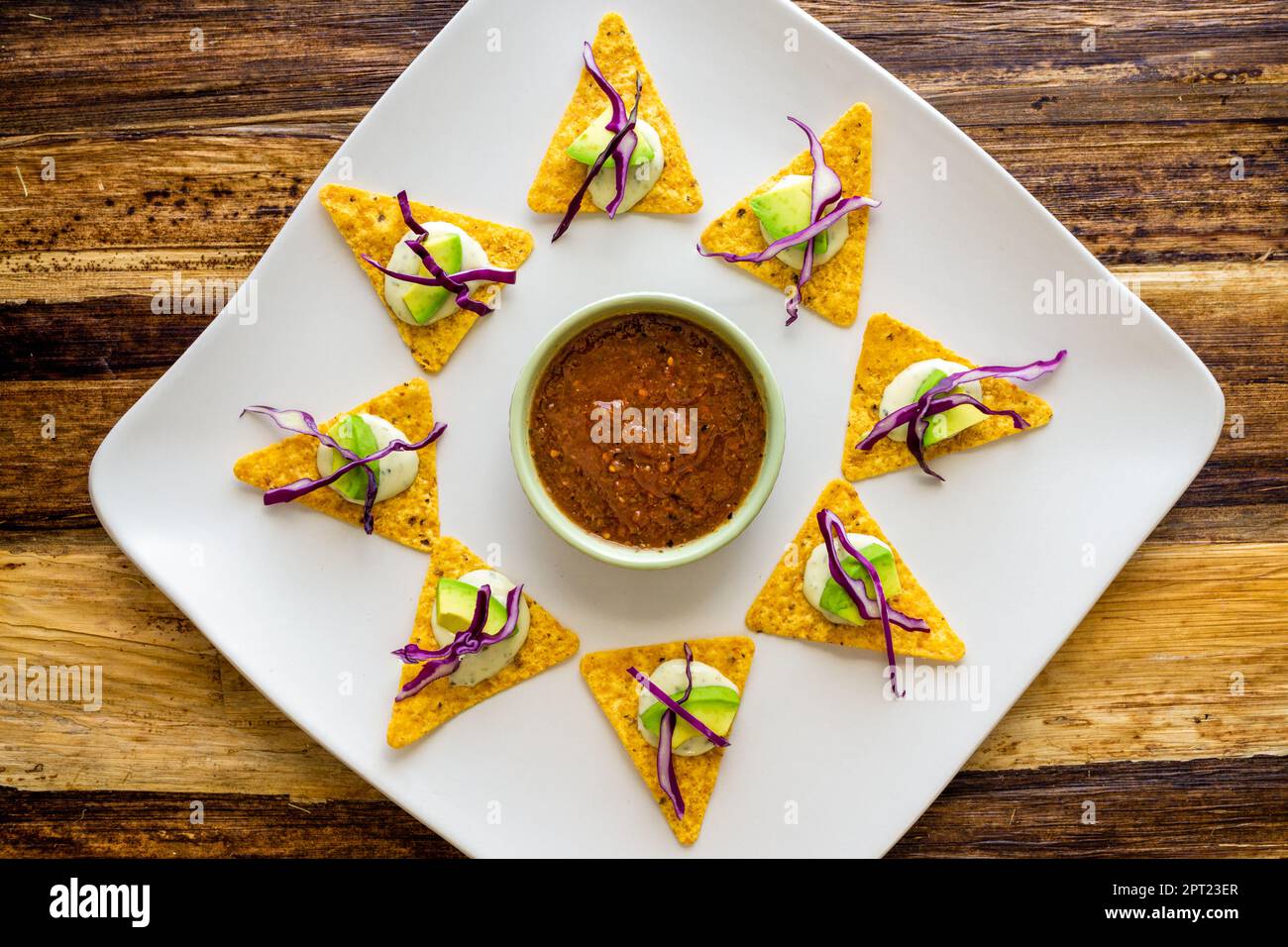 Tortilla-Chips auf einem Teller mit Salsa in der Mitte. Über Schuss. Stockfoto