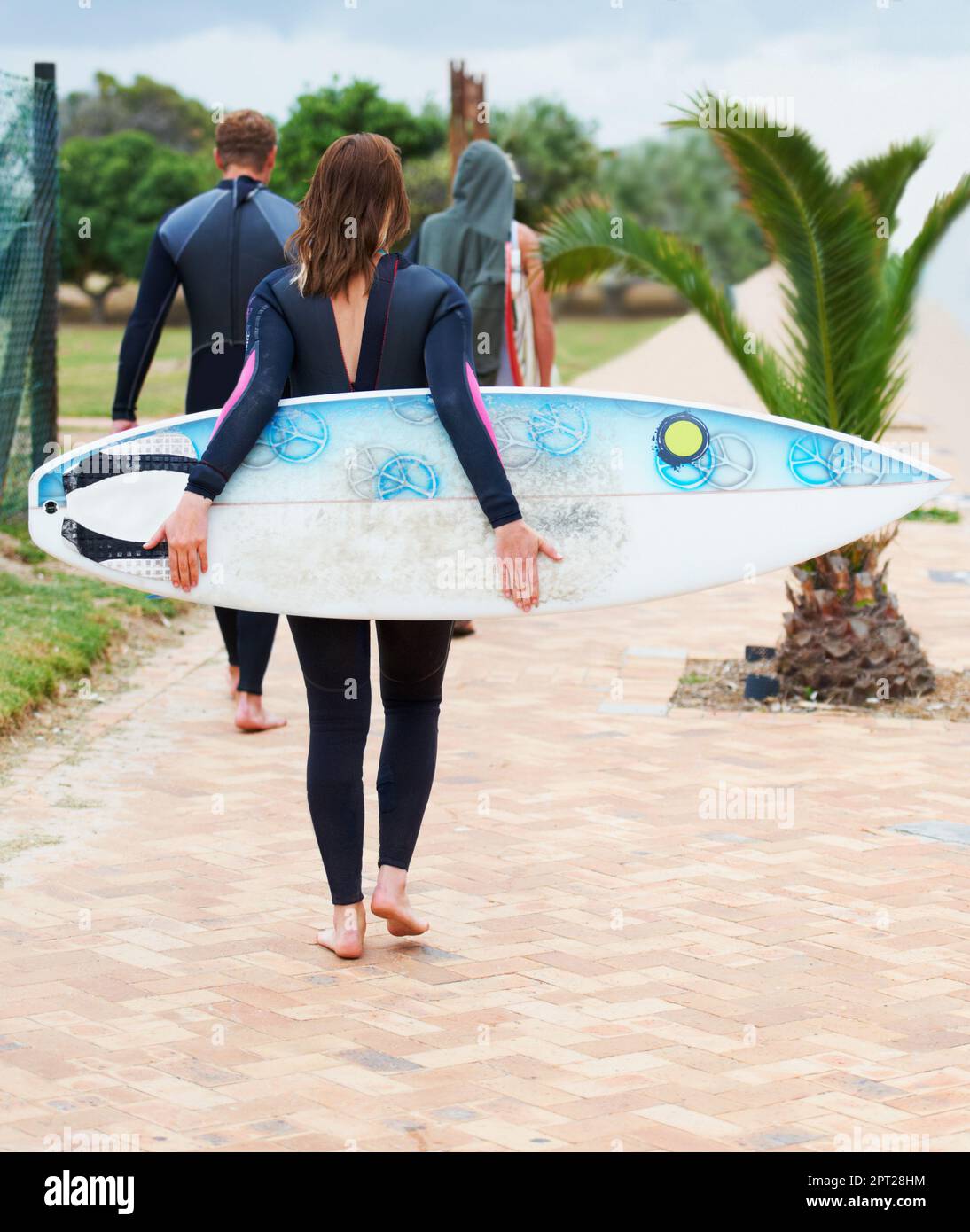 Wenn die Wellen anfangen zu rufen... Antworten Sie. Surfer, die in Neoprenanzügen auf den Strand zugehen Stockfoto